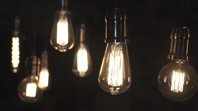 Vintage style light bulbs swinging on the wire in the house. Decorative lights at home. Old Edison bulb.