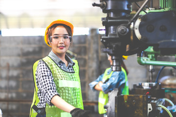 Woman worker wearing safety goggles control lathe machine to drill components. Metal lathe...