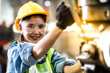 Woman worker wearing safety goggles control lathe machine to drill components. Metal lathe industrial manufacturing factory