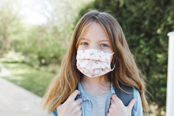 pretty girl with nose mouth mask and school bag goes to school after corona quarantine