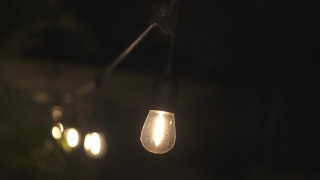 Warm lighting, vintage garland of lamps or glass lantern, electric bulbs shining, decoration for holiday.