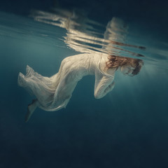 Girl in a sequined dress swims underwater