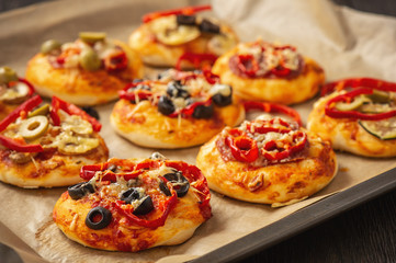 Homemade mini pizza with salami, pepper, olives and cheese.