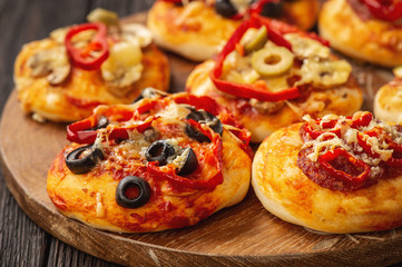 Homemade mini pizza with salami, pepper, olives and cheese.