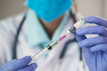 Doctor  hand in blue nitrile gloves holding flu, measles, coronavirus vaccine. covid-19 virus, Corona virus Vaccine concept with syringe and blue hand gloves.