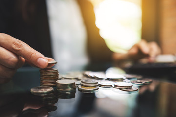 Businesswoman calculating and stacking coins on the table for saving money and financial concept