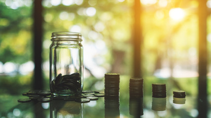 Coins stack and a glass money jar on the table for saving and financial concept