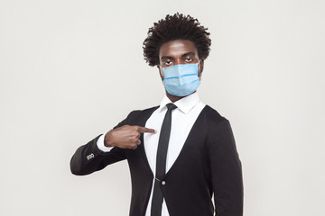 It's me. Portrait of proud young worker man wearing black suit with surgical medical mask standing...