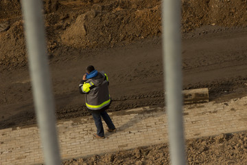 male worker foreman builder phoning in work clothes at construction site sand