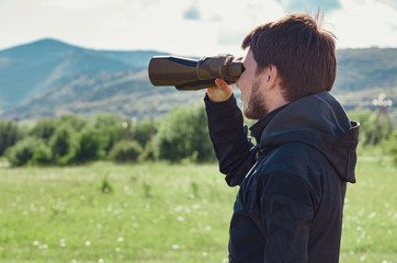 Young man at mountain looking through binoculars
