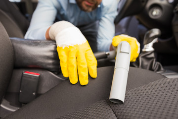 Handyman vacuuming car front seat with vacuum cleaner