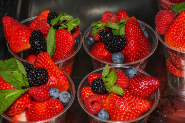 Closeup of many red whole fruits like strawberries, blackberries