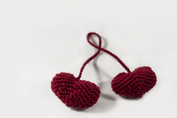 Two red attached crocheted amigurumi hearts isolated