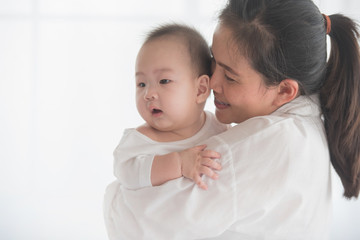 happy loving family. mother playing with her baby in the bedroom. asian mother hugging and holding her baby. family, motherhood, parenting, family and child care concept. White background.