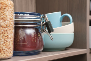 Passport in a jar with lid closed on the lock on kitchen shelf. Concept of banning visits to other countries during a pandemic.