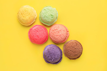 Set of ice cream scoops of different colors and flavors on yellow table, copy space. Food background, summer refreshing concept, traditional seasonal cold sweets