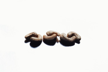 On a light background peeled cashew nuts are scattered. Hazelnuts on a mirror background