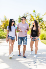 Obraz premium Young handsome man and two women friends walking in the summer street near beach and talking have fun together,