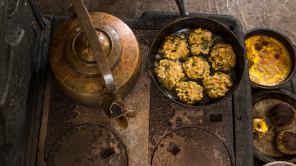 An ancient stove with a kettle and a frying pan in an American house