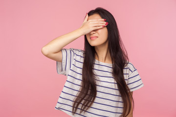 Don't want to watch! Portrait of confused girl with long hair in striped t-shirt hiding eyes,...