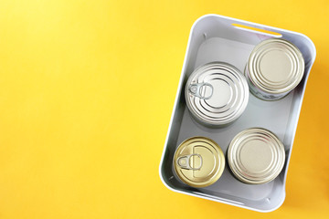 Donation. Food donations on a yellow background. Closed canned beef, pork, corn, green peas in a box. The view.