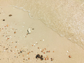 Soft ocean waves and rock fragments background sand beach.