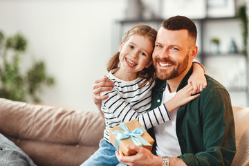 Cute girl hugging happy father with gift.