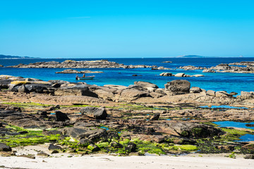 Empty beach in the Illa de Arousa island in the Rias Baixas in Galicia, Spain, with a fishing boat close to the shore.