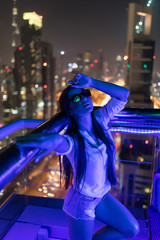 Fototapeta na wymiar Young woman standing on the view of night light skyscrapers
