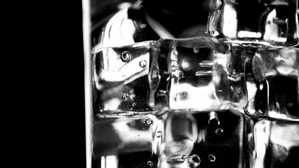 Closeup pouring clean fresh Water in a Glass with splash and bubbles, isolated on Black background. Ice, bubbles and splash. Cold tonic Mineral water. Healthy lifestyle. Living water. Drinking water.