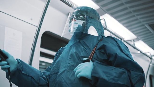 Cleaner with protective suit, face shield and medical mask disinfecting train. Prevention of the coronavirus spread