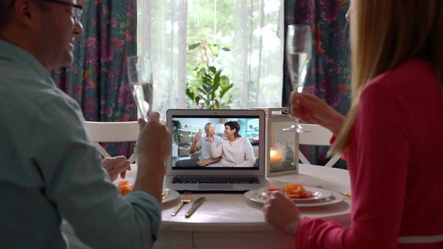 A young couple and an elderly couple celebrate together Using Laptop Video Call. Social distancing, self isolation during quarantine