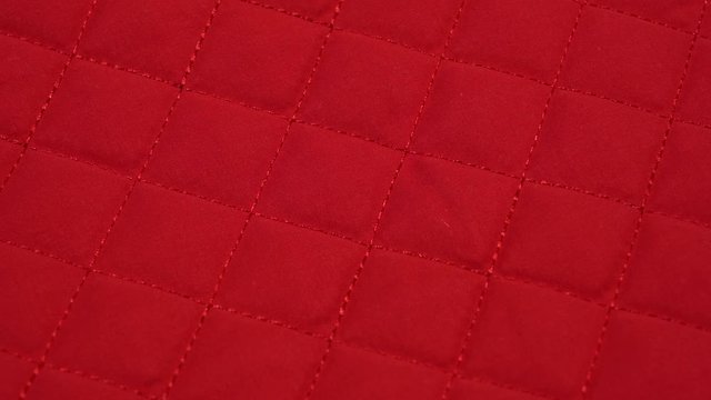 Closeup view video of bright red quilted texture of fabric.