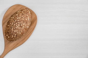 Whole bread with seeds and flakes on wooden board on white background.