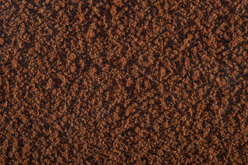 Brown background of sprinkled instant coffee with a strong increase