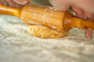 Close-up of female hands with freckles rolling pin revealing dough