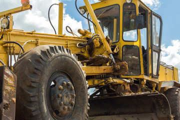 Yellow grader close-up on a background of blue sky. Road special equipment.