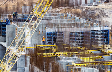 Construction workers install formwork and iron rebars or reinforcing bar for reinforced concrete partitions at the construction site of a large residential building.