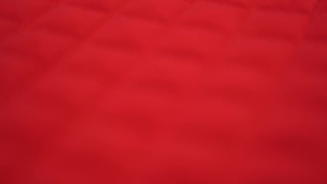 Closeup view video of blurry defocused bright red quilted texture of fabric.