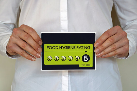 Restaurant manager holds a sticker with Food Hygiene rating 5 from The United Kingdom Food Standards Agency
