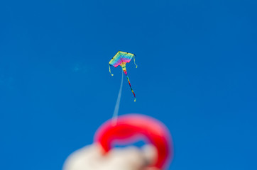 hand launches a colored kite in a blue sky