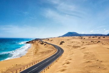 Fototapeta na wymiar Rocky coastline and highway with golden sand and blue water