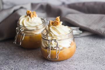 Delicious dessert in a jar. Banana dessert with caramel and whipped cream, garnished with cookies...