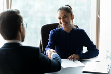 Smiling businesswoman hr manager shaking successful candidate hand after interview, congratulating...