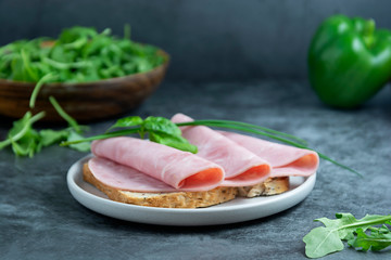 Ham sandwich. Pork ham slices over wholegrai bread over dark background.