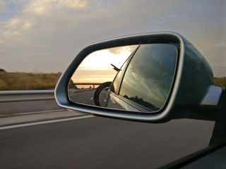 Fototapeta na wymiar View in rear mirror on roadtrip with bikes on back of car