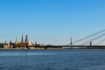 Fototapeta premium Panoramic view of opposite bank of the river Daugava. View at the Old Town of Riga and church towers.