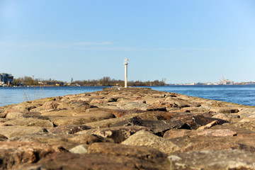 Fototapeta na wymiar A rocky pier circles the harbor. A beacon at the end of the pier. 