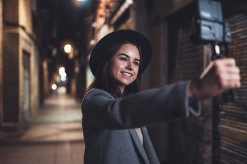 Traveler female blogger shooting video for vlog social media with digital camera. Smile happy woman vlogger taking photo selfie on background night city