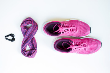 Pink running shoes for women and headphones on a white background